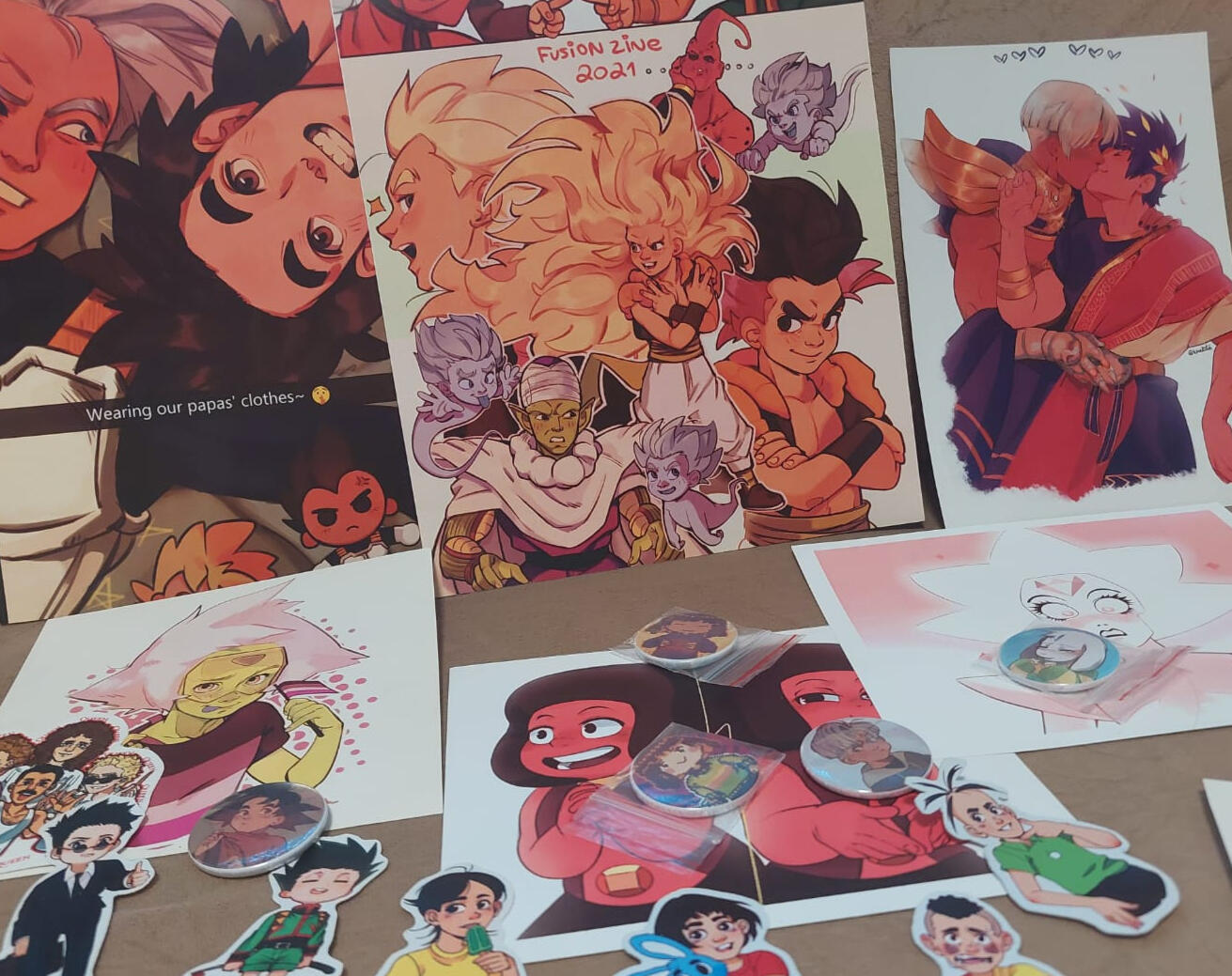 Produtos (2026) Variedade que inclui prints, bottons e adesivos.